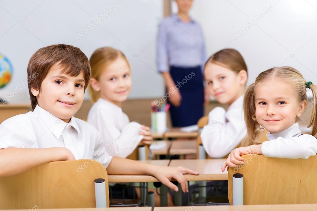 Gruppo di bambini con zaini davanti a una scuola di paese